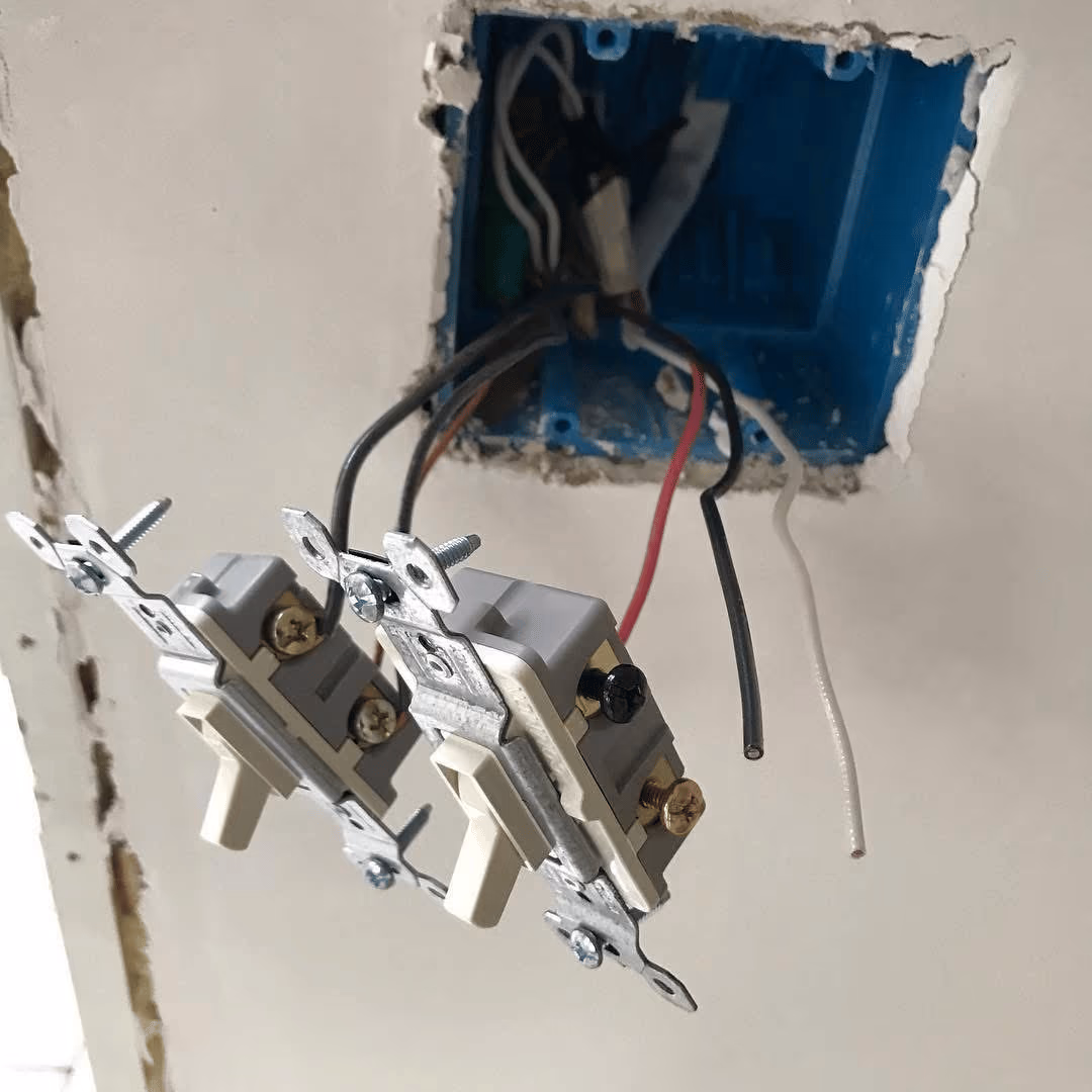 Light switches pulled from a wall box with the wiring exposed