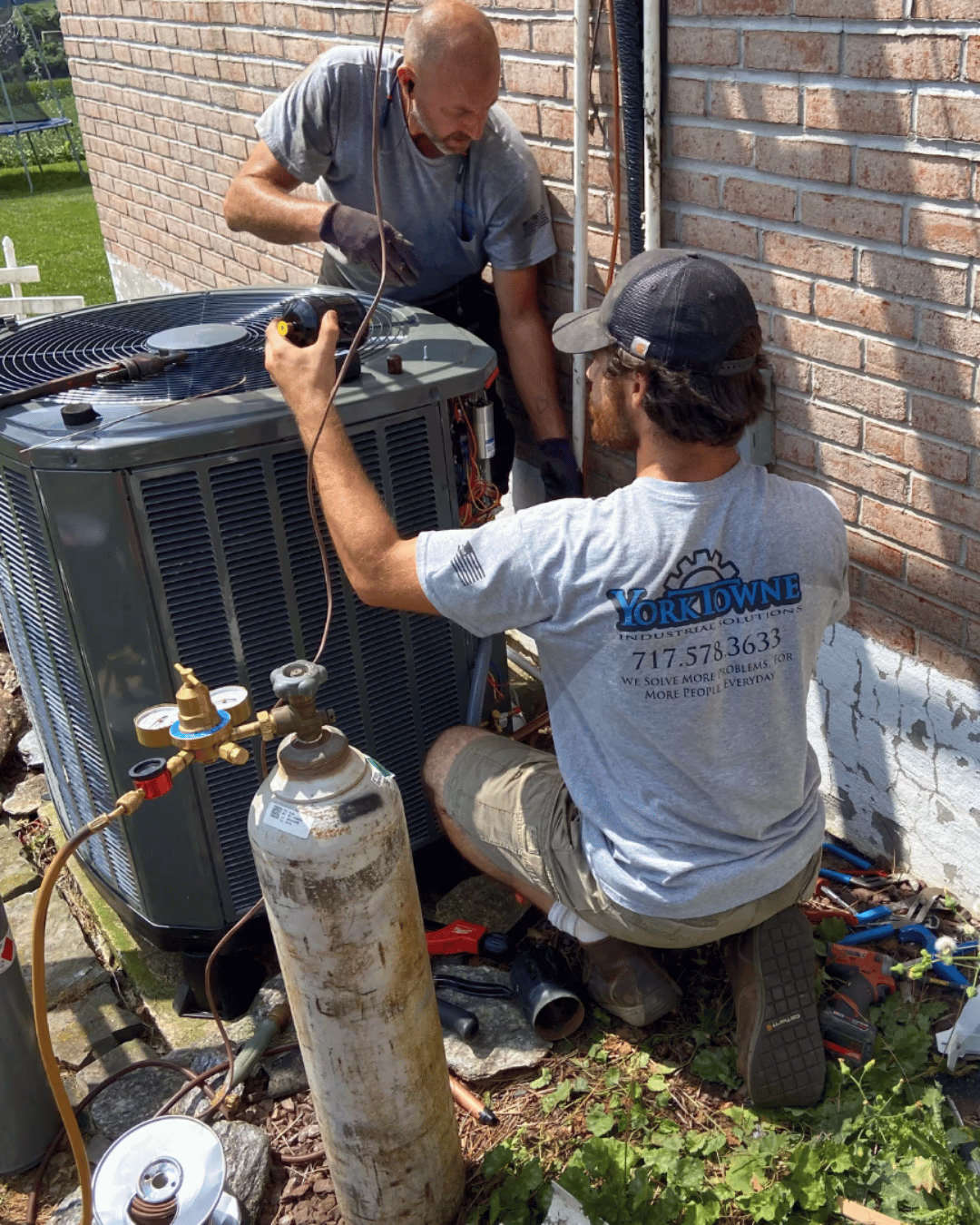 Two Yorktowne technicians servicing an outdoor air conditioner