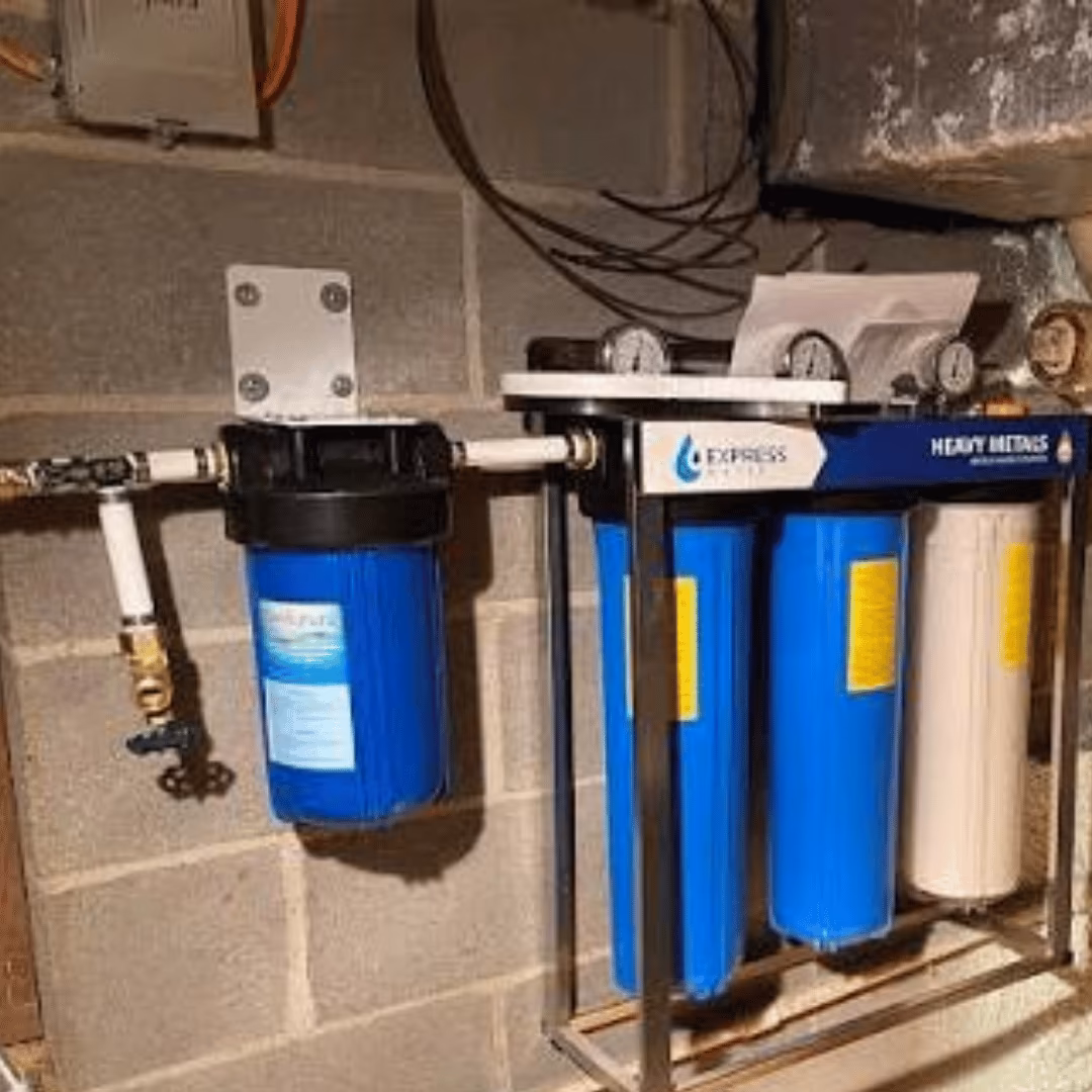 Whole-home water filter canisters mounted on a block wall