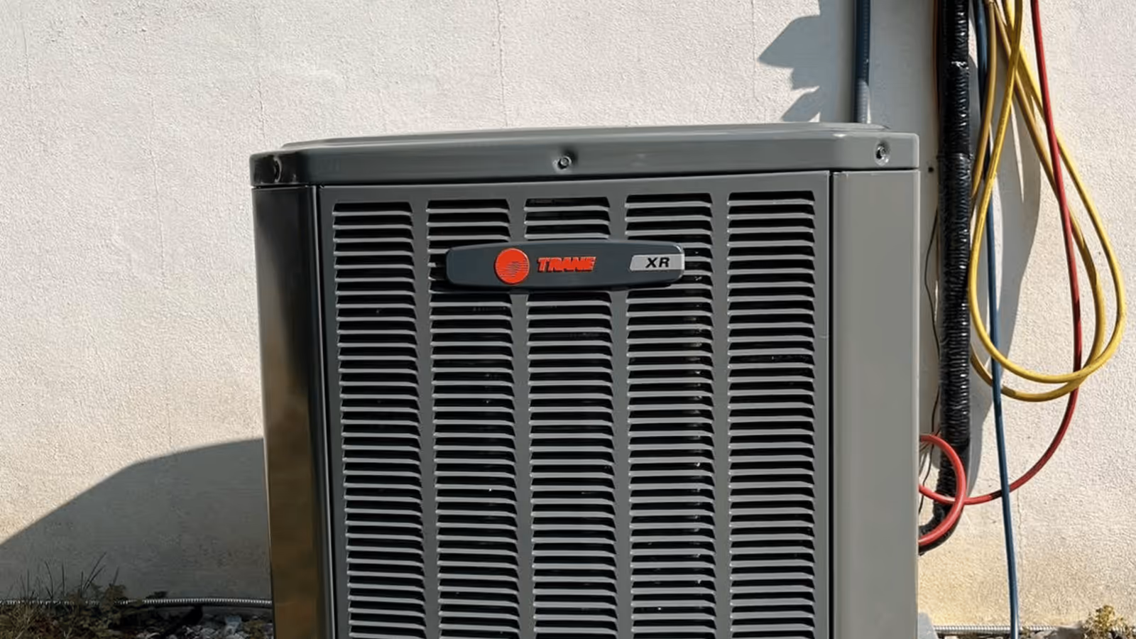 Outdoor air conditioning condenser beside a home