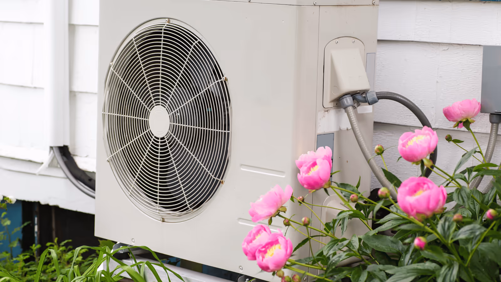 Outdoor heat pump unit mounted beside a home